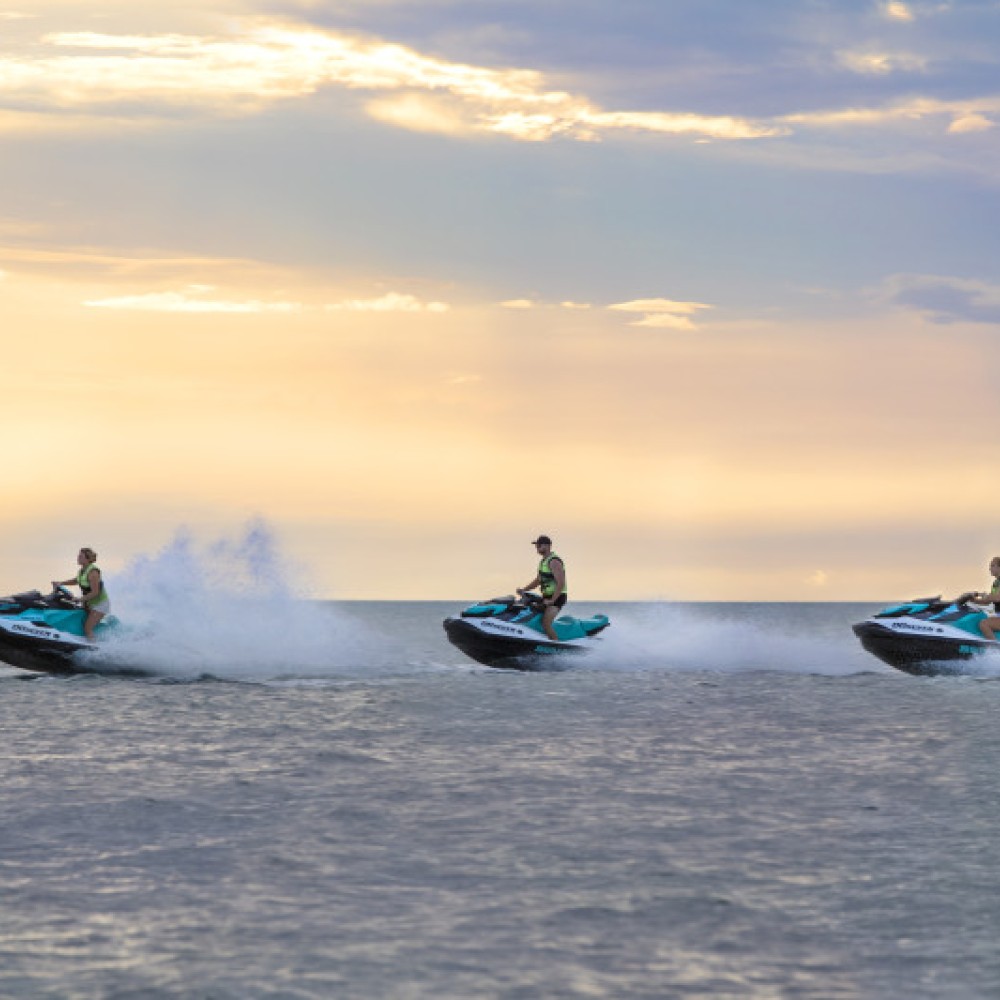 3 jet skis on the ocean during sunset 