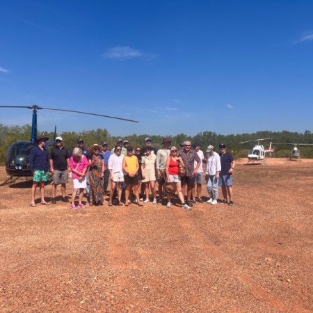 Group of people standing in front of helicopter 
