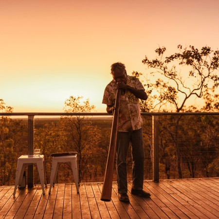 Person playing digeridoo with sunset in background 