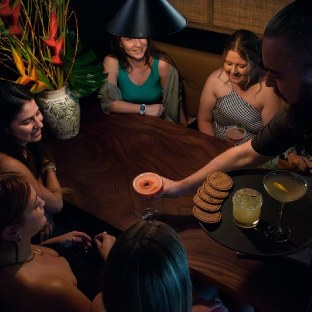 Group of people getting served a cocktail in dimly lit venue 